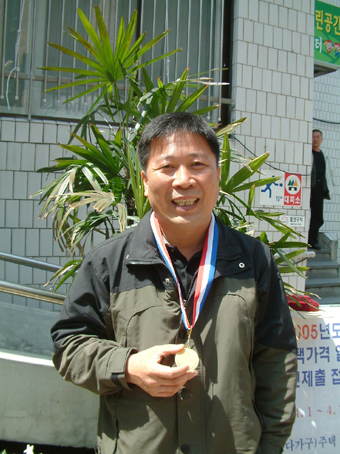 김용선 씨가 좋은나라 운동본부에서 받은 천사 금메달을 목에 걸고 밝게 웃고 있다.